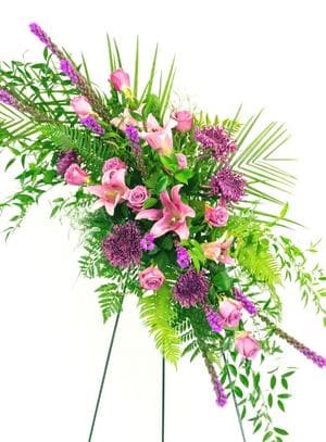 A standing spray designed with pink lilies, lavender mums, lavender roses, and liatrus accented with foliage.